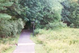 The path crosses the pipeline area and enters the woods.