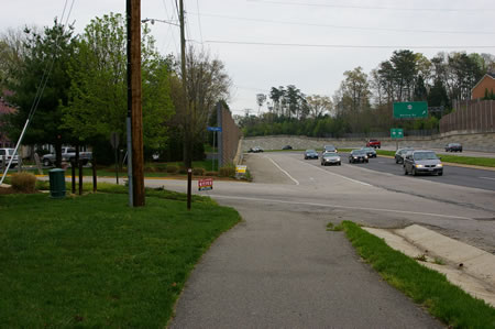 Turn left at the first intersection and follow the sidewalk to a point opposite the asphalt trail on the other side of that road.