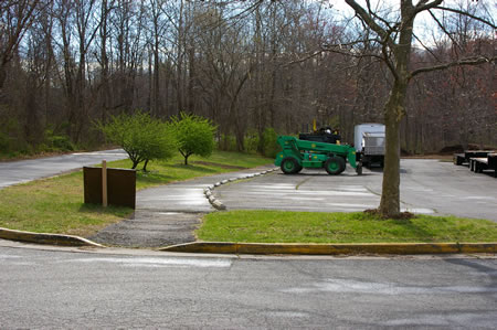 The trail goes to the end of the parking lot and turns right to cut across the lot.