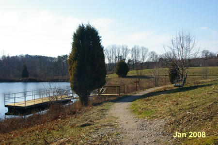 The trail passes a dock and a bench next to the pond.
