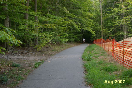 A dirt trail intersects from the left.  Continue on the asphalt trail.