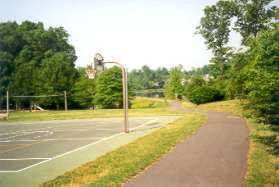 The path is adjacent to basketball courts on the left.