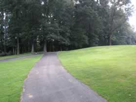 The trail crosses the golf course and a golf cart path just prior to a wooded area.