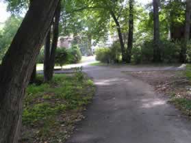 The trail crosses a golf cart path and continues between the homes.