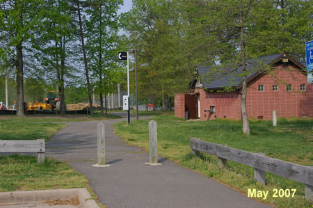 Take the asphalt trail on the north side of the parking lot and walk west toward  the building on the right.