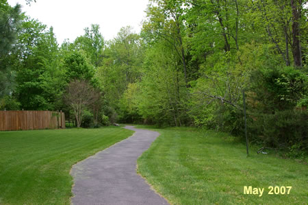 The trail passes behind houses on the left.