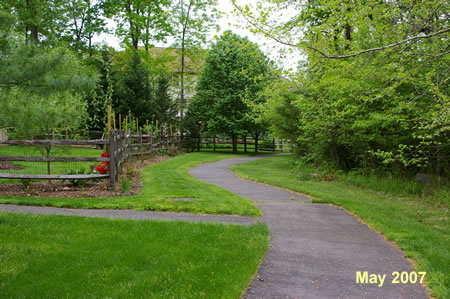 An asphalt trail intersects from the left. Continue straight on the present trail.